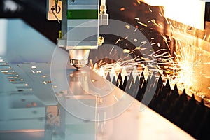 Laser cutting. Metal machining with sparks on CNC laser engraving maching photo