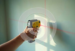 Laser distance measurer projecting red lines on wall surface