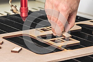 Laser engraver working and engraving wooden board with hand