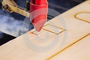 Laser engraver working and engraving wooden board with smoke