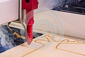 Laser engraver working and engraving wooden board with smoke