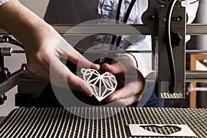 Laser engraving and cutting, woman holding an example of a cut out wooden heart