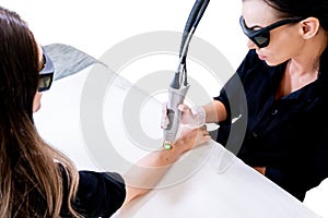 Laser hair removal session with beauty technician and female patient, epilating arm hair, in a cosmetology skin clinic