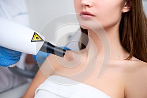 Laser mole removal on a woman`s chest in a beauty salon. Hardware cosmetology. Beautician doctor removing birthmark or