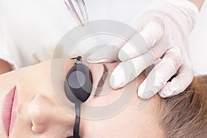 Laser removal of permanent eyebrow makeup. A young woman undergoes laser removal of permanent makeup in a salon.