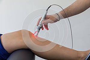 Laser therapy on a knee used to treat pain.
