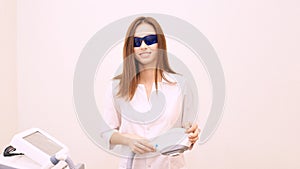 Laser unwanted hair cosmetology procedure. Beautiful young girl hold hand. Blue glasses. Removal treatment. IPL machine