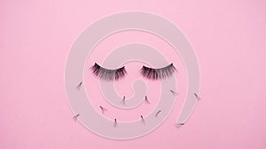 Lashes loss and extension concept. Fake eyelash fall on pink background. Makeup.