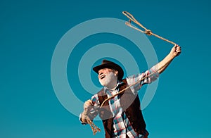 Lasso throwing. Old wild west cowboy with rope. Bearded western man with brown jacket and hat catching horse or cow.