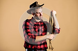 Lasso tool of American cowboy. Western life. Man cowboy beige background. Man wearing hat hold rope. Ranch occupations