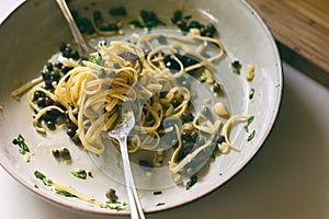 Last bite of fresh linguine with garlic, olive oil, black olives, capers and fresh basil. Close up overhead view.