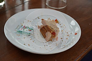 Last bite of a vegetable sandwich kept on plate. Side view shot of a piece bread with tomato with the last bit