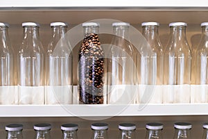 The last bottle of coffee beans sits on a shelf among many other empty glass bottles. macro photo.