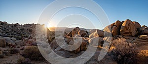 Last light of sunset behind rocks and bouldrs in panoramic view of desert landscape on a sunny January day with clear blue sky in