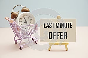Last Minute Offer text message for promotion with alarm clock and shopping trolley cart on pink and blue background