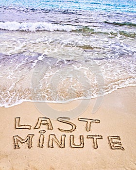 Last Minute written on sand, with waves in background