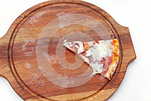 Last one slice of delicious Italian pizza with ham and cheese on wooden board on white table. Pizza time. Top view. Close-up