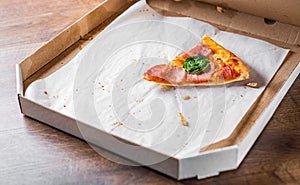 Last one slice of Pizza with Mozzarella cheese, ham, bacon, Tomato sauce, pepper, Spices and basil. Italian pizza in cardboard box