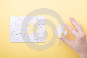 Last piece jigsaw in hand White puzzle Concept success of business Yellow background