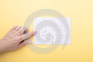Last piece jigsaw in hand White puzzle Concept success of business Yellow background