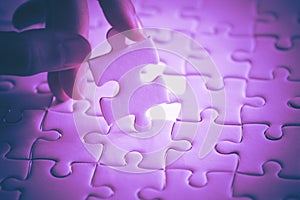 Last piece of white plain jigsaw holding by hand, step of success concept, ultraviolet