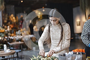 The last steps in completing the Christmas wreath at the flower shop counter.