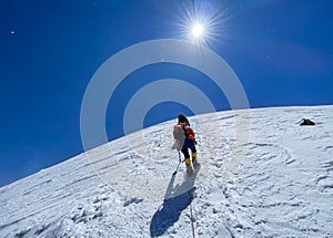 Last steps before Kazbek Kazbegi summit 5054m rope team dressed mountaineering clothes, boots with crampons ascending by snowy