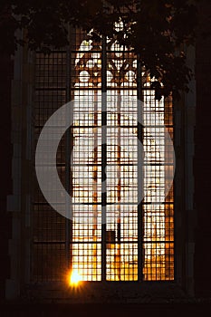 Last sunlight from the setting sun radiates atmospherically through stained glass windows of an old gothic church in a historic o