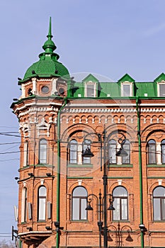 last two floors of old historical building dating from 1899 with red walls and green roof.