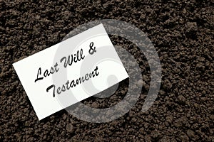 Last will and testament concept. A piece of written paper on grave soil.
