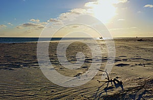 Late afternoon on deserted wide beach with boat on ocean