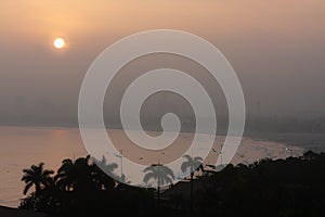 Late afternoon at Enseada beach, GuarujÃ¡, with the sun turning pink in the fog, Brazil