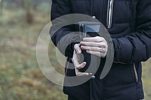 In late autumn, men`s hands are warming themselves on a black toggle switch with a hot drink. Environmentally friendly use of photo