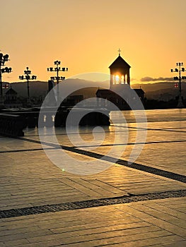 Late evening bryght sunset sun rays enlighten through the small chapel arches near the Holy Trinity Cathedral of Tbilisi, Georgia