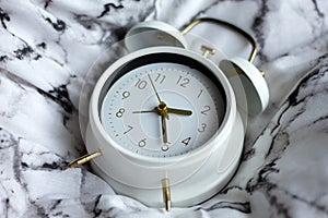 Late morning in bed. Classic white alarm clock