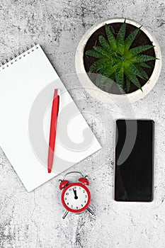 Late time on clock. Smart phone, red alarm clock and notebook on wooden background. Deadline concept