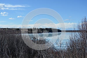 Late-winter landscape of melting ice on lake with reflection