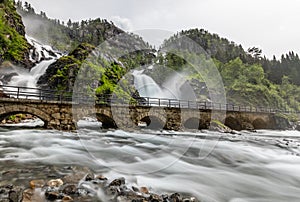 Latefoss twin waterfalls streams under the stone bridge archs, Odda, Hordaland county, Norway