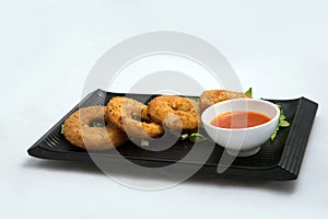 Lateral Hero shot of an appetizer platter of onion rings with lettuce and tomato chutney on a minimal white background with