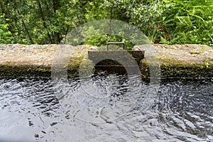 lateral metal door in a levada channel to divert irrigation water to another channel, Portuguese island of Madeira. photo