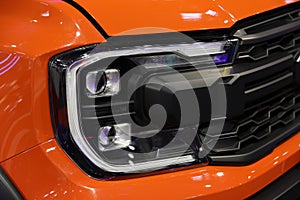 Lateral view of a new model Ford Raptor with radiator grill,logo Ford and headlights detail close up.