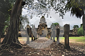 Laterite stone paved walkway with free-standing stone posts to the courtyard gates of ancient Khmer temple built of red sandstone