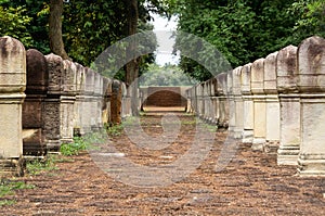 Laterite stone paved walkway with free-standing stone posts to the gates of ancient Khmer temple built of red sandstone and lateri