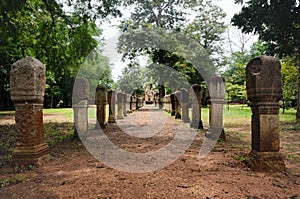 Laterite stone paved walkway with free-standing stone posts to the gates of ancient Khmer temple built of red sandstone and lateri