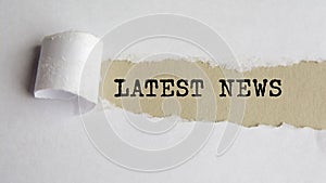 latest news. text on brown paper under a torn white paper sheet, business concept