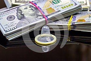 Latex condom with dollar packs on black background. Sex, love for money and prostitution concept