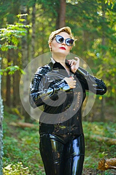 Latex rubber fashion woman walking in the forest