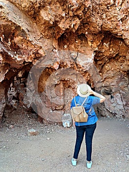 Latin adult woman geologist with hat explores and investigates opal mine, studies the minerals and analyzes the red land