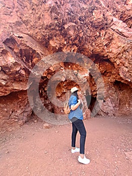 Latin adult woman geologist with hat explores and investigates opal mine, studies the minerals and analyzes the red land