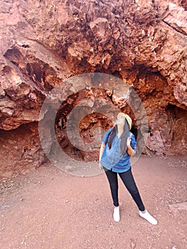 Latin adult woman geologist with hat explores and investigates opal mine, studies the minerals and analyzes the red land